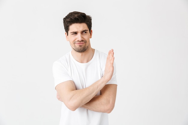 Image of displeased young man posing isolated over white wall  make stop gesture.