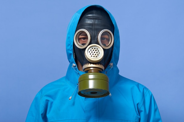 Image of ecologist wearing gas mask frights with pouring dangerous chemicals to ground