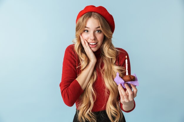 Image of european woman 20s wearing red beret holding birthday cake with candle