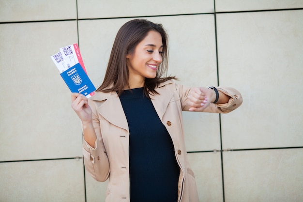 Image of European Woman Having Beautiful Brown Hair Smiling While Holding Passport and Air Tickets