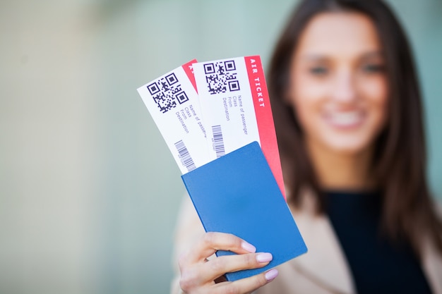 パスポートと航空券を押しながら笑顔美しい茶色の髪を持つヨーロッパの女性のイメージ