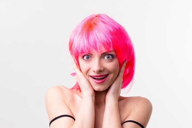 분홍색 배경에 격리된 사탕을 들고 포즈를 취하면서 웃고 있는 가발을 쓴 흥분한 아름다운 여성의 이미지