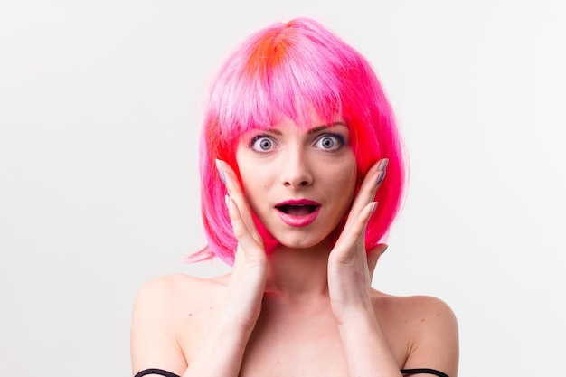 Image of excited beautiful woman in wig laughing while posing with candy isolated over pink background