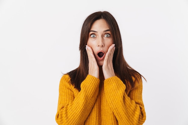 Image of excited brunette adult woman wearing sweater expressing surprise and wonder with open mouth isolated on white