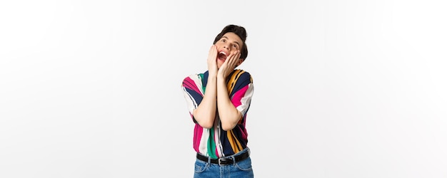 Image of excited gay man shouting of joy and looking up feeling ecstatic standing against white background