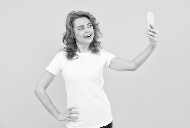 Image of excited happy young woman isolated overyellow background make selfie by camera