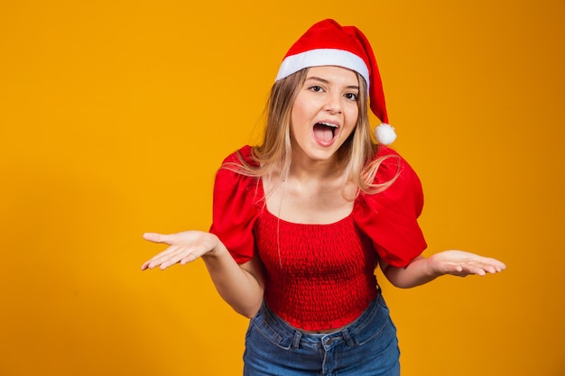 Image of excited screaming young man standing isolated over yellow background with Santa Claus hat looking at camera with copy space.