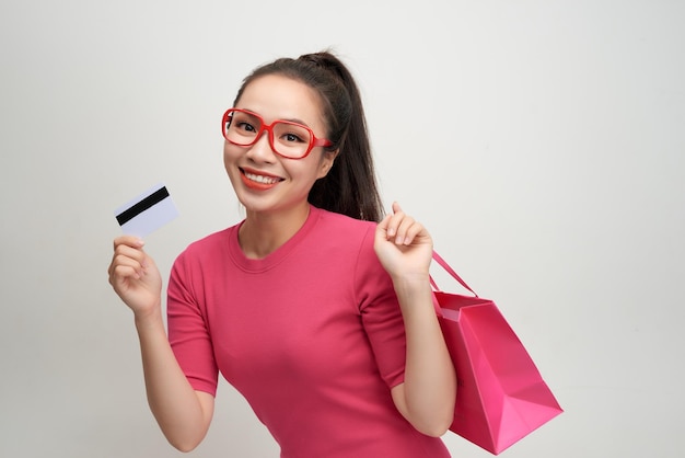 Image of excited screaming young woman standing holding shopping bags and credit card