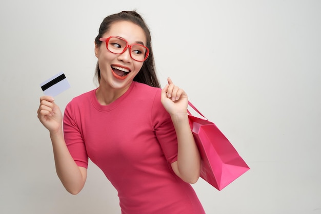 Image of excited screaming young woman standing holding shopping bags and credit card