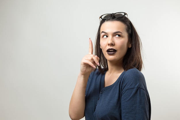 Image of excited young lady with glasses. Looking camera have an idea. Stands on a white background.