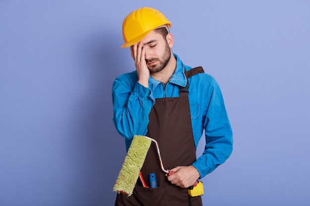 Image of exhausted professional builder wearing brown apron