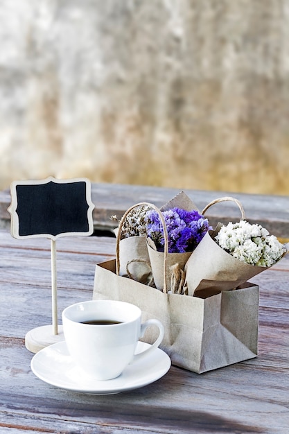 Image of flower bouquet and coffee cup on wooden table background.