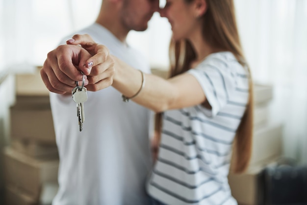 Image focus technique. House keys. Cheerful young couple in their new apartment. Conception of moving.