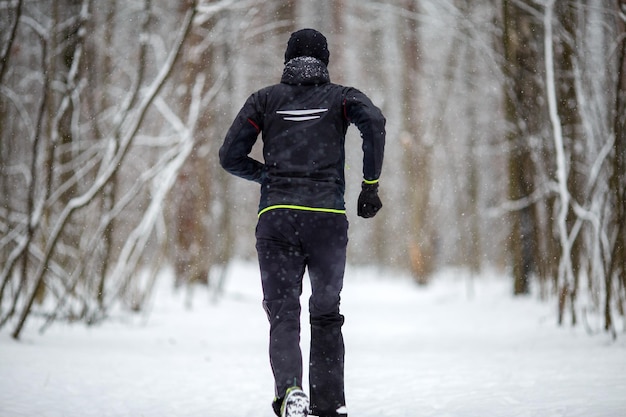 Изображение со спины мужчины в спортивной одежде, бегущего зимой