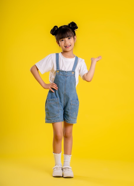 Image full body of asian little girl posing on a yellow background