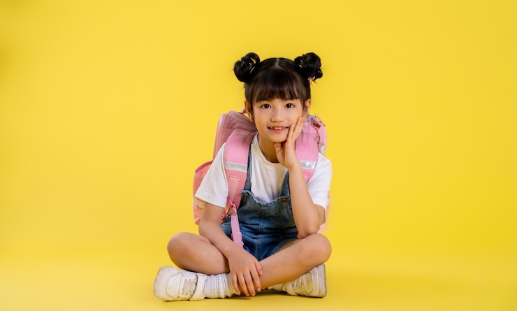 Photo 黄色の背景にポーズをとってアジアの少女の全身画像