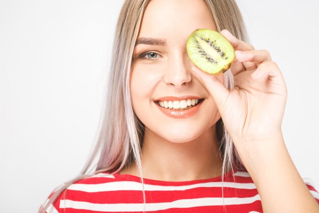 Image of funny young lady standing over white background while holding kiwi