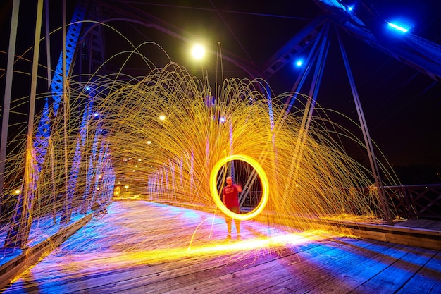 Image of Ghostly man in middle of a ring of yellow sparks at night on a bridge