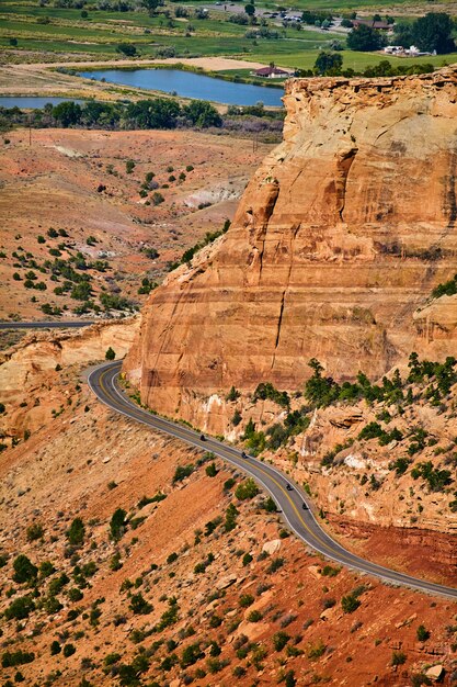 Image of Giant red rock cliffs in canyon with road and motorcycles driving through