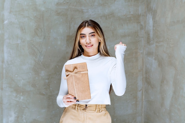 Image of a girl model holding a paper present over stone 