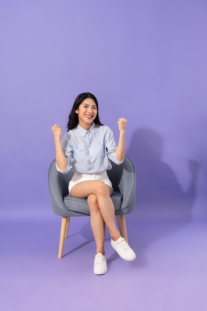 Image of girl sitting on sofa isolated on purple background