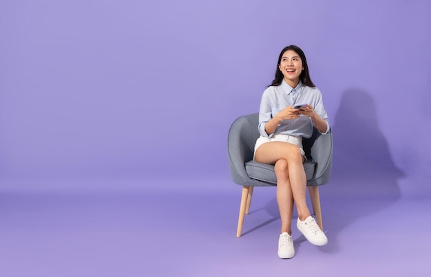 Image of girl sitting on sofa isolated on purple background