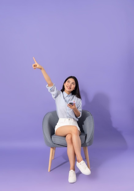 Image of girl sitting on sofa isolated on purple background