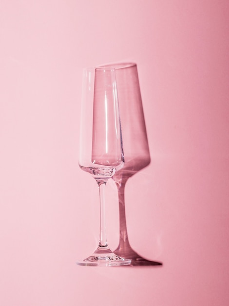 Image of a glass goblet with a hard shadow on a pink background. Glassware in hard light.