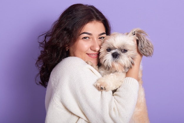 Image of good looking brunette holding Maltese in both hands