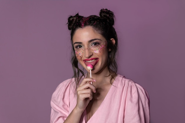 ピンクの背景に分離されたロリポップを食べてゴージャスなブロンドの女の子 20 代のイメージ