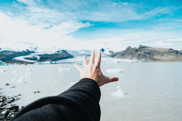 아이슬란드 겨울 여행 추운 날씨 개념에서 빙하 앞에서 남자에게 손을 보여주는 이미지