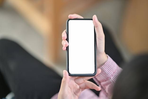 Image of hands holding black mobile phone with blank screen