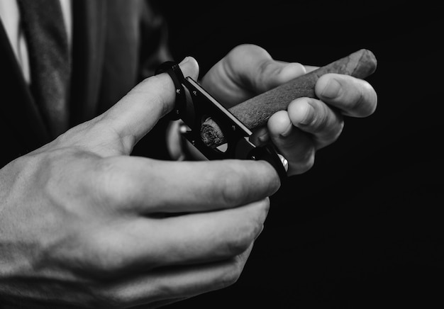 Image of hands holding a guillotine and a cigar. cigar clubs\
concept. mixed media