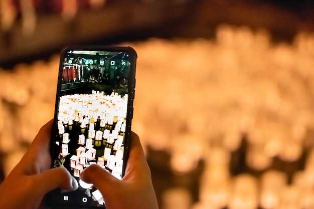 Image of Hands with cellphone taking picture of Paper Lanterns on Water as Asian event