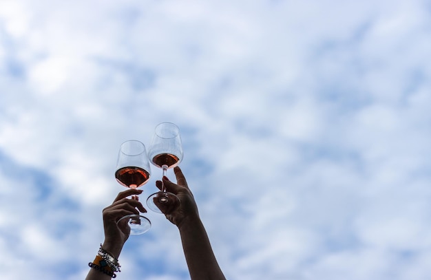 Immagine delle mani di una giovane coppia femminile che brinda con bicchieri di vino