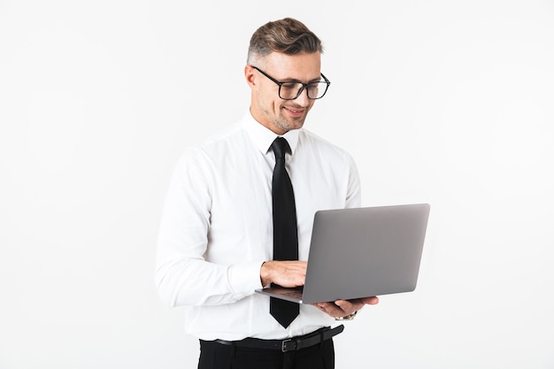 Image of a handsome cheerful business man isolated over white wall using laptop computer.