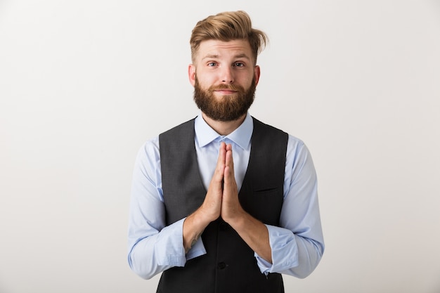 Image of a handsome young bearded man standing isolated over white wall make hopeful please gesture.