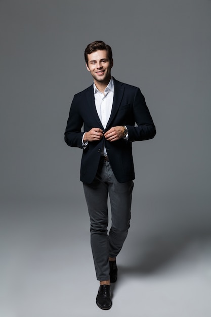 Image of a handsome young business man isolated over grey wall wall posing.