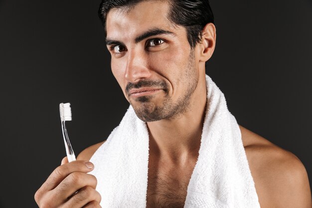 Image of a handsome young man posing isolated brushing cleaning his teeth.