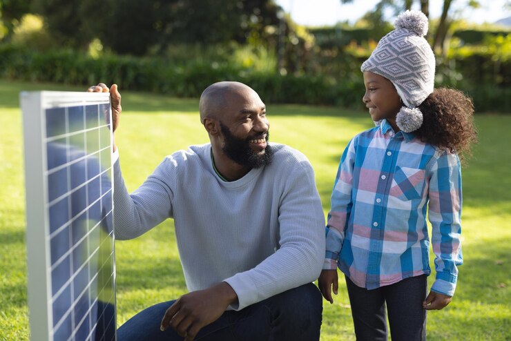 Image of happy african american father showing solar panels to daughter. Family, green energy and eco awareness concept.