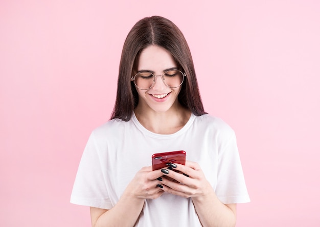 Image of happy american woman smiling and using cellphone isolated over pink wall