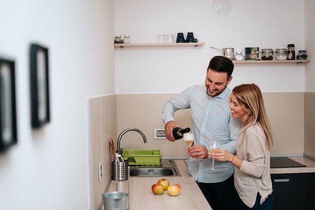 Image of happy couple with glasses of wine, pouring wine.