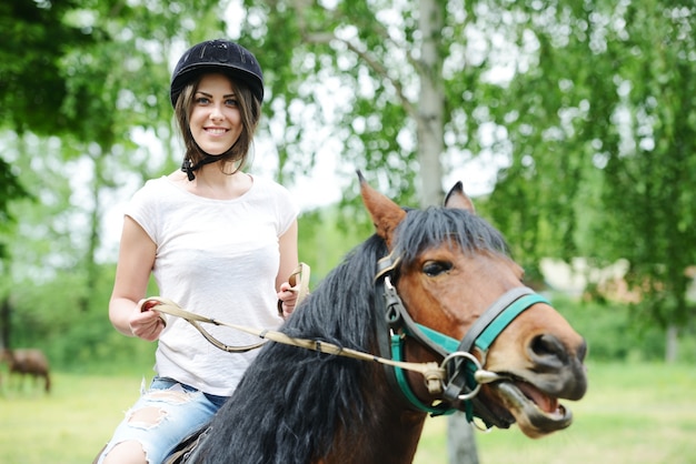 村の農場で馬に座っている幸せな女性のイメージ