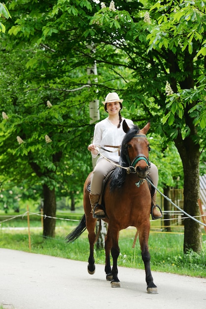 村の農場で馬に座っている幸せな女性のイメージ