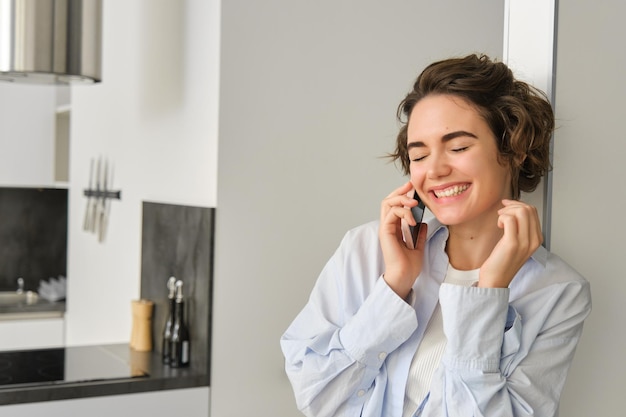 幸せな女性が携帯電話で話しスマートフォンを使ってチャットし笑い笑顔を浮かべています