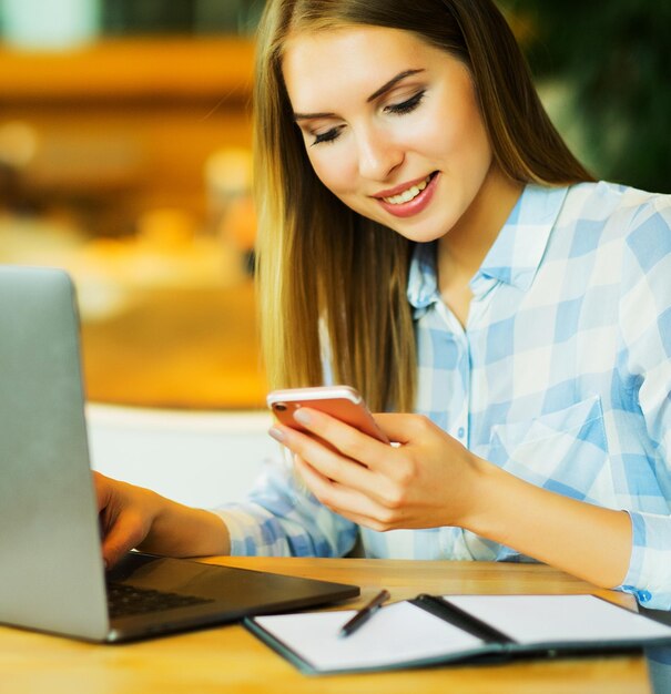 Image of happy woman using laptop and smartphone in cafe Lifest