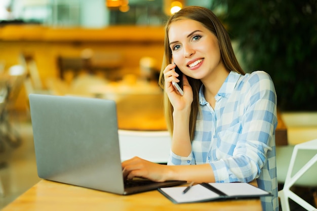 Image of happy woman using laptop and smartphone in cafe Lifest