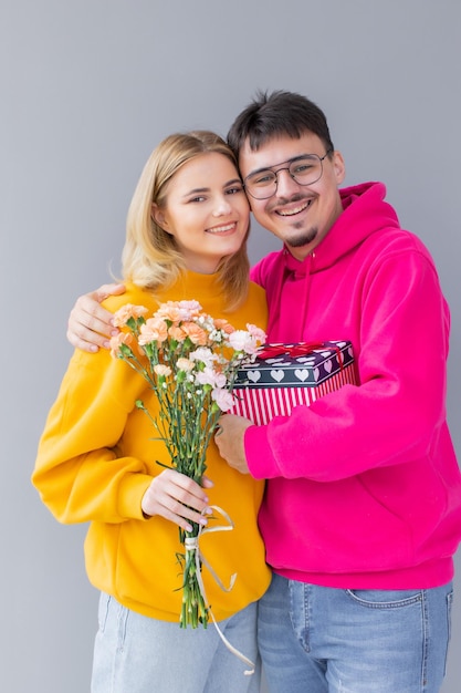 Image of happy young loving couple isolated holding gift present box and flowers