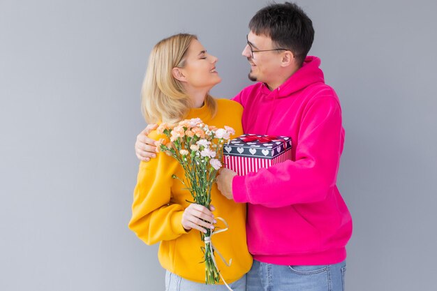 Image of happy young loving couple isolated holding gift present box and flowers