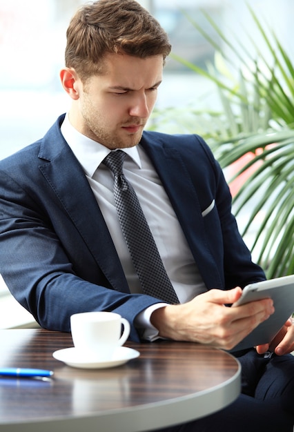 Image of happy young man using digital tablet in cafe